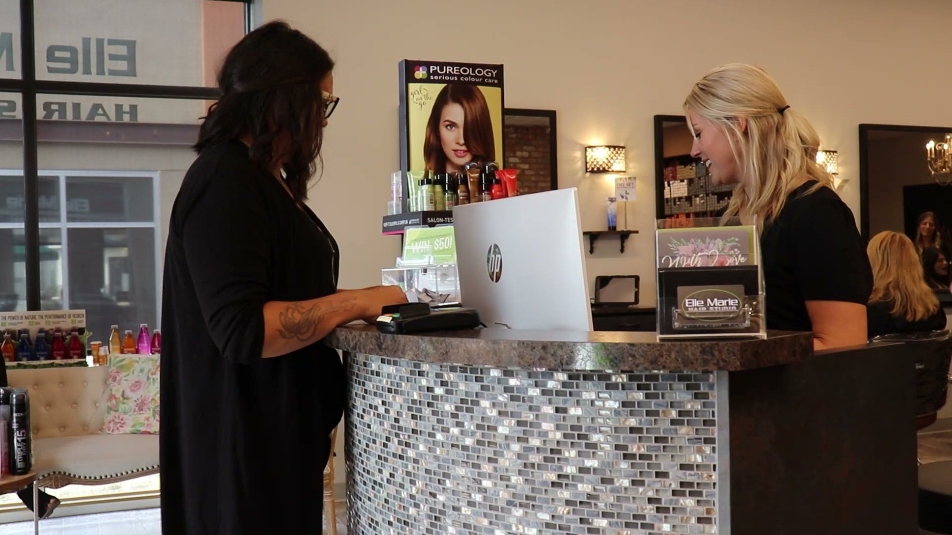 Photo of Ali, Salon Manager at Elle Marie Hair Studio in Snohomish, assisting a guest at the front desk.